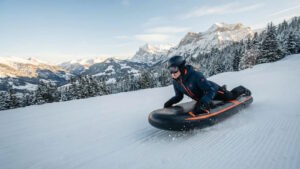 Airboarding: Airboarden als Trendsportart, Technik, Varianten und Sicherheit 6 Das Bild zeigt eine Person beim Airboarding an einem schneebedeckten Hang in alpinem Gelände.