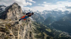Base-Jumping – B.A.S.E. jumping genau erklärt: Risiken, Technik, Geschichte und wichtige Fakten 1 Das Bild zeigt einen Extremsportler beim Wingsuit Flying in den Alpen, der sich von einer Klippe stürzt.