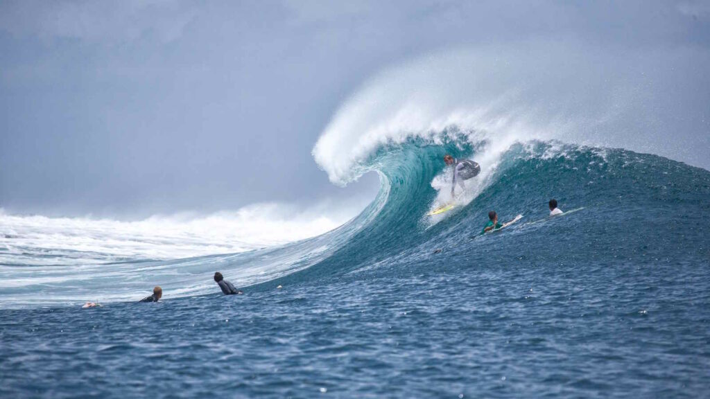 Big Wave Surfing: Große Wellen, Extremsport und die Wissenschaft hinter dem Big Wave Surfen 1 Im Bild sieht man eine große Welle und mehrere Surfer beim Big Wave surfen.
