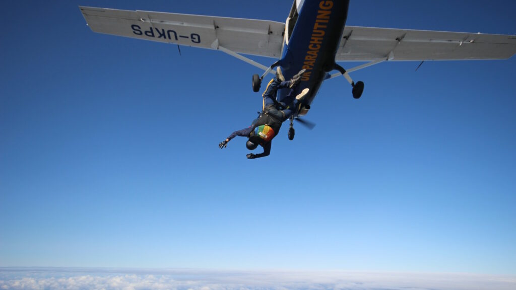 Fallschirmspringen: Ultimativer Guide mit Tipps zu Sicherheit, Vorbereitung, Kosten und mehr 1 Das Bild zeigt einen Extremsportler beim Fallschirmspringen, der sich gerade aus dem Flugzeug stürzt.