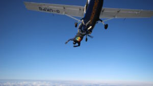 Das Bild zeigt einen Extremsportler beim Fallschirmspringen, der sich gerade aus dem Flugzeug stürzt.
