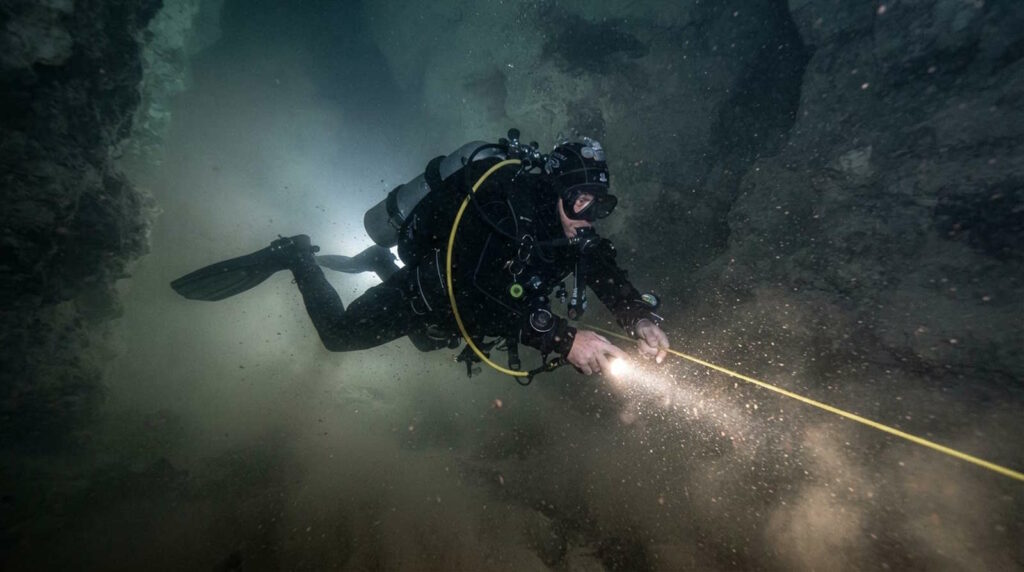 Höhlentauchen entdecken: Guide für Ausbildung, Ausrüstung, Sicherheit und faszinierende Unterwasserwelten 4 Im Bild sieht man einen Höhlentaucher, der ein Silt-Out ausgelöst hat durch seinen Flossenschlag. Das Wasser ist sichtbar trüb und die Sicht behindert.