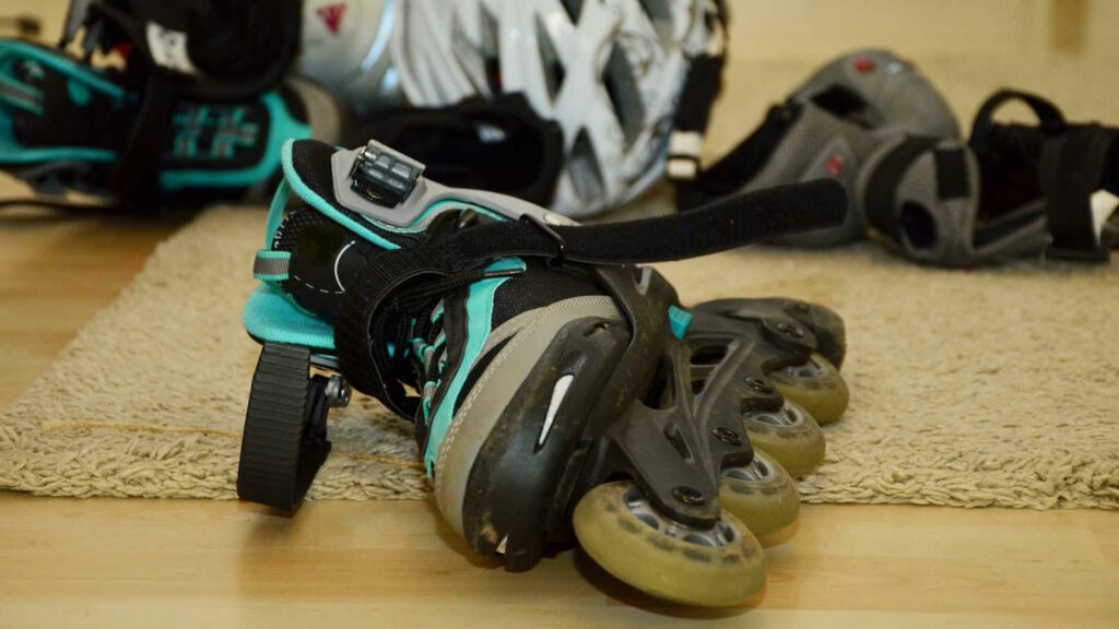 Inline-Skating lernen: 10 wichtige Tipps für Anfänger 2 Das Bild zeigt die Ausrüstung, welche man beim Inline-Skating benötigt. Dazu gehören Inline Skates mit je vier Rollen, Helm und Schutzausrüstung für Knie und Ellenbogen.