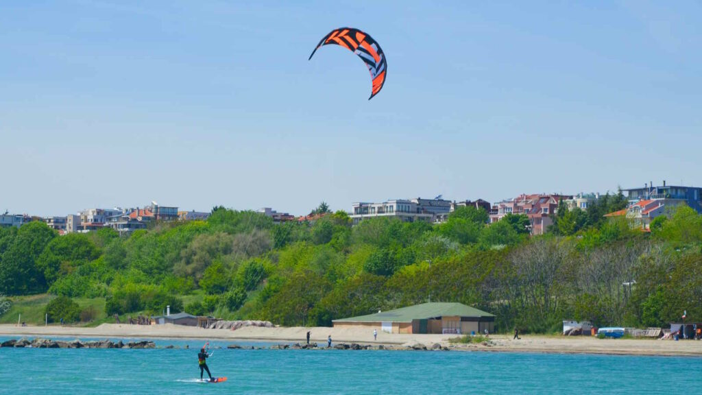 Kitesurfen: Der umfassende Guide für Einsteiger und Fortgeschrittene mit Tipps 2 Im Bild sieht man einen Kitesurfer inklusive des Kite in der Nähe eines Strandes