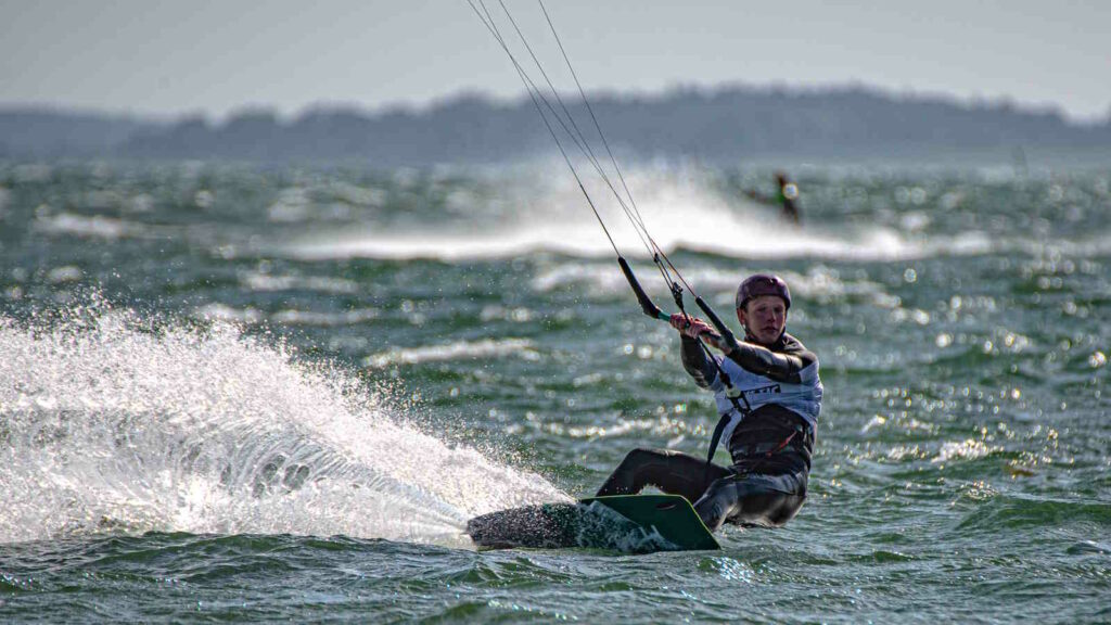 Kitesurfen: Der umfassende Guide für Einsteiger und Fortgeschrittene mit Tipps 1 Im Bild sieht man eine Frau beim Kitesurfen auf dem offenen Meer.