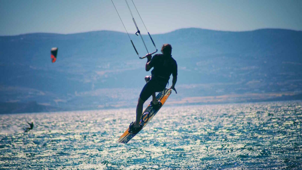 Kitesurfen: Der umfassende Guide für Einsteiger und Fortgeschrittene mit Tipps 3 Das Bild zeigt eine Person beim Kitesurfen, der gerade zu einem spektakulären Sprung ansetzt.