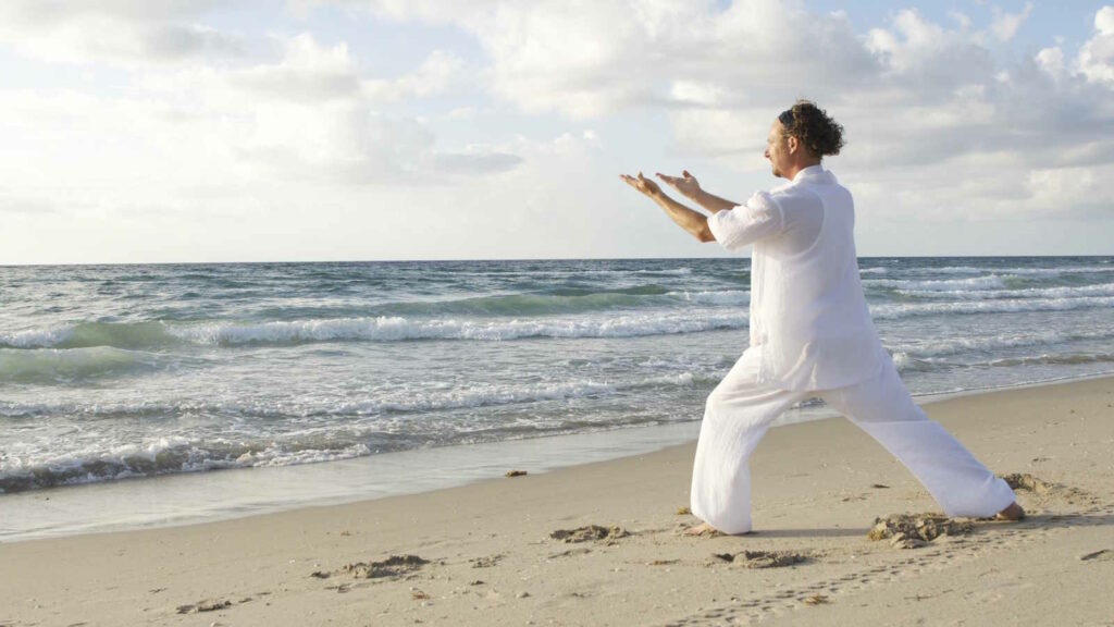Tai Chi: Wirkung, Übungen, Prinzipien und die traditionelle chinesische Kampfkunst verständlich erklärt 2 Das Bild zeigt einen Mann beim Tai Chi am Strand